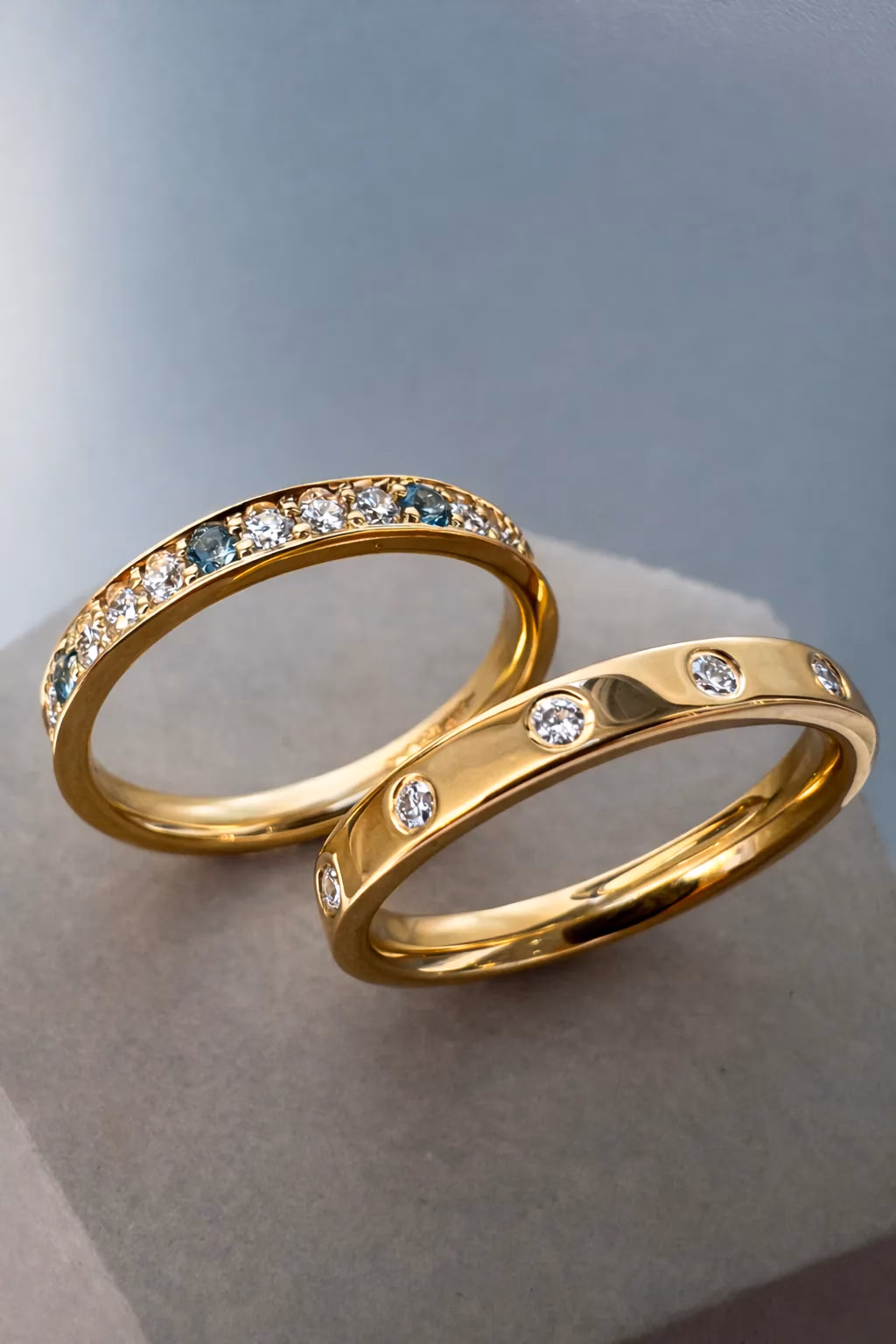 Two Stacking Rings in 18ct Yellow Gold, one flush set with spaced out diamond and one with grain set diamonds, aquamarine and topaz.