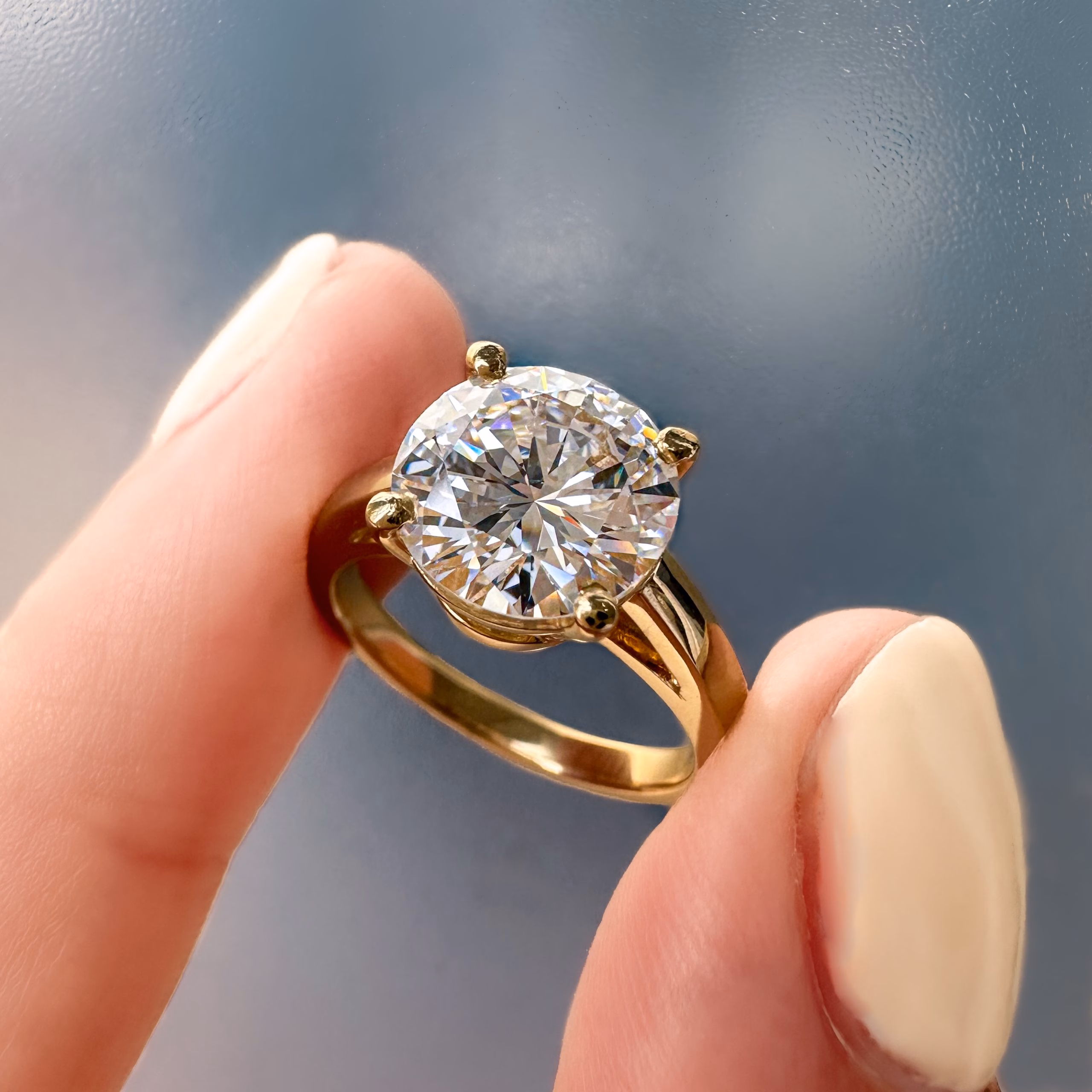 Custom diamond ring being held between two fingers
